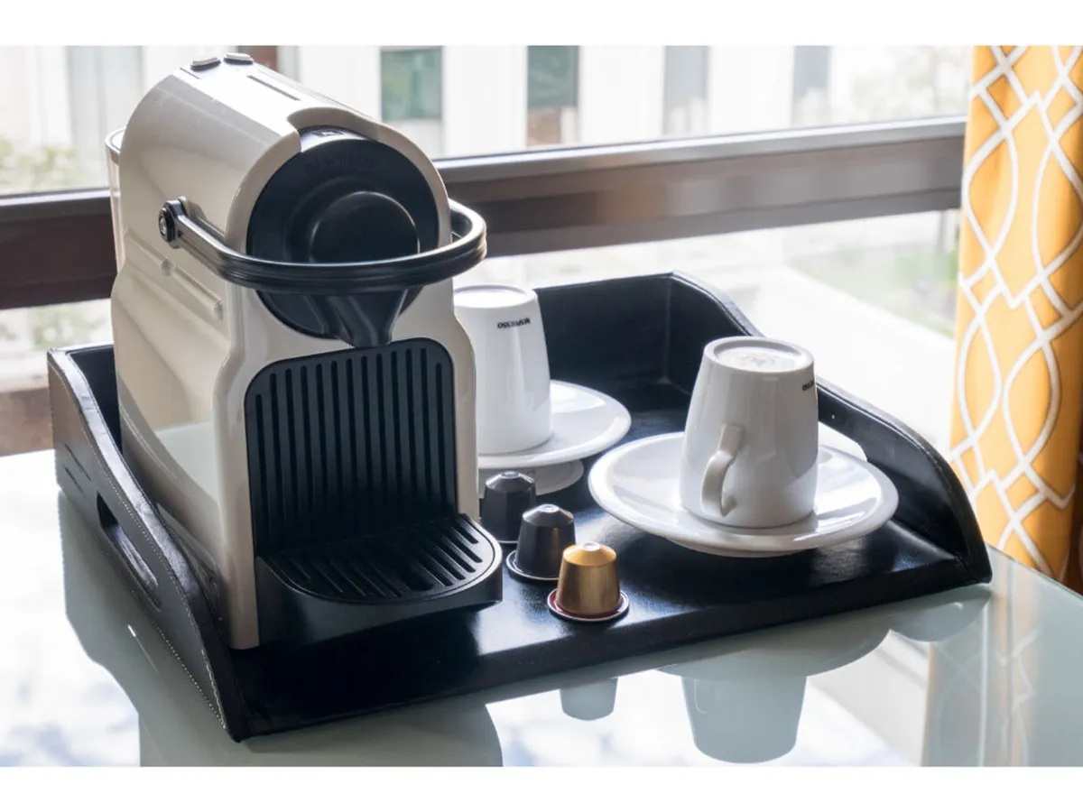 A cozy coffee station in a guest room, complete with a modern coffee machine, cups, coffee pods, and a tray. The arrangement invites guests to start their day with a freshly brewed beverage, emphasizing the sense of thoughtful hospitality.