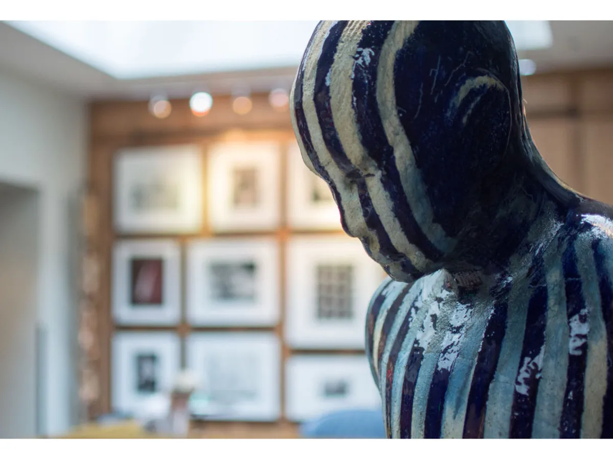 An inspiring interior space within Hotel Lucia, featuring a gallery wall adorned with framed artwork and a striking striped sculpture. The setting encourages art appreciation, conversation, and connection, nodding to the hotel’s unique collection of Pulitzer-winning photographs.